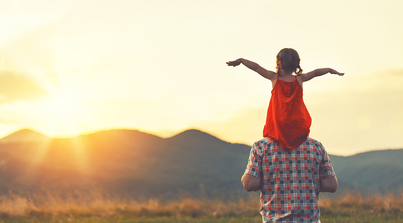 man and girl on shoulders at sunset